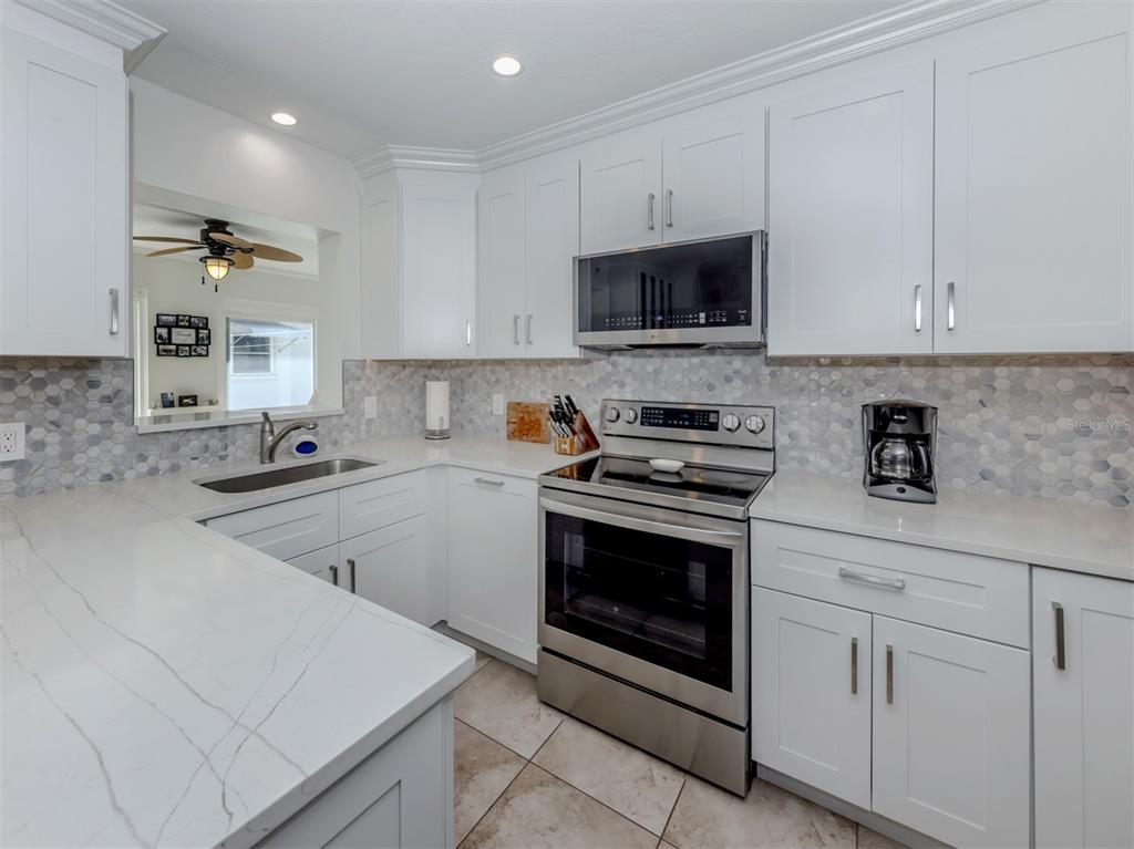 1977 Beach Road, Unit 83 Englewood, FL 34223 - Photo 5 of 48 a kitchen with stainless steel appliances granite countertop a sink a stove a microwave and cabinets