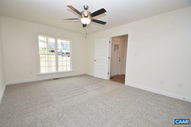 an empty room with windows and fan