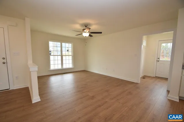 an empty room with wooden floor and windows