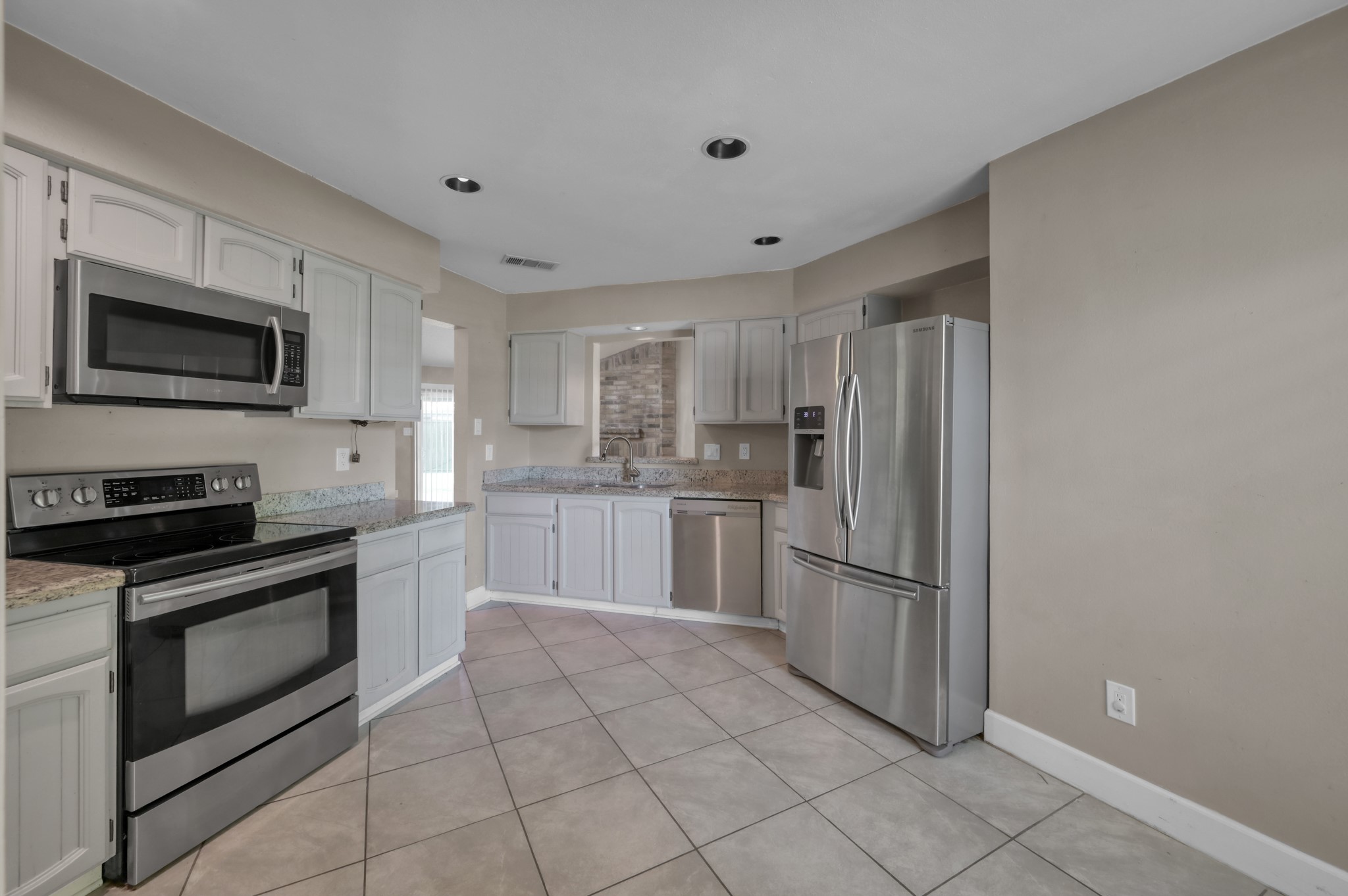 12015 Fallbrook Drive Houston, TX 77065 - Photo 12 of 29 This modern kitchen features stainless steel appliances, including a double-door refrigerator and built-in microwave. The space is accented by sleek cabinetry, granite countertops, and a neutral tile floor, offering a clean and inviting atmosphere.