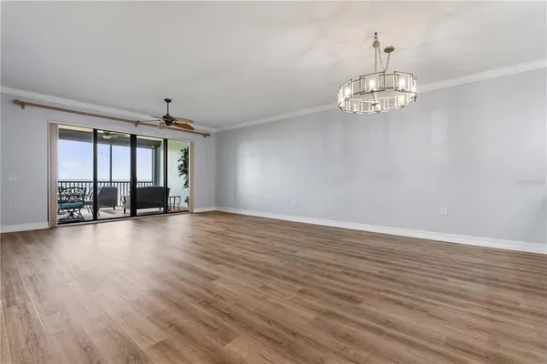 an empty room with wooden floor and a ceiling fan