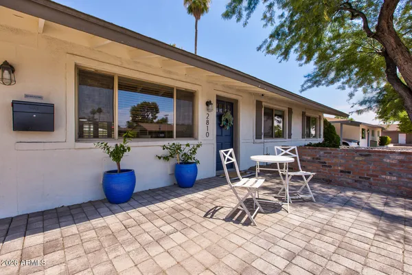 a view of a patio with table and chairs potted plants and a large tree