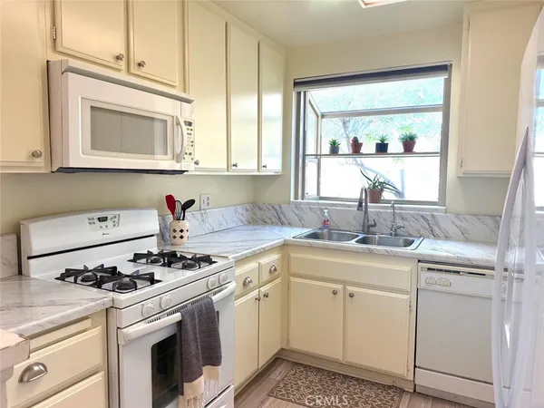 a kitchen with cabinets appliances a sink and a window