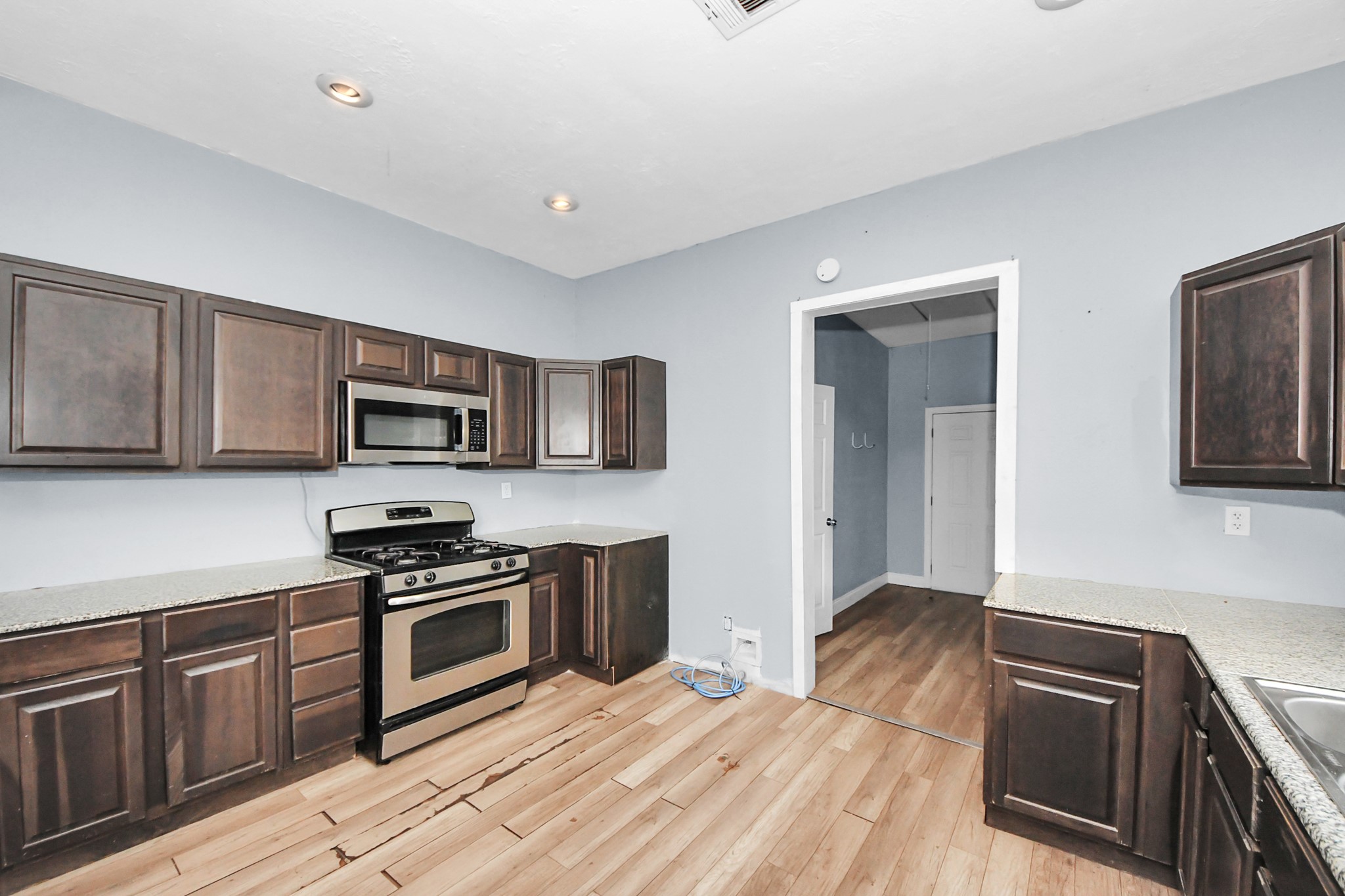 15 High Street Baytown, TX 77520 - Photo 8 of 29 a kitchen with stainless steel appliances granite countertop a stove top oven a sink dishwasher a microwave oven with cabinets and wooden floor