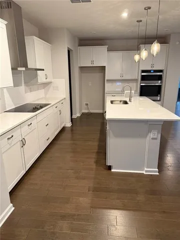 a kitchen that has a lot of white cabinets and stainless steel appliances