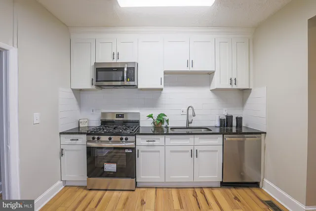 a kitchen with stainless steel appliances granite countertop a sink a stove and microwave