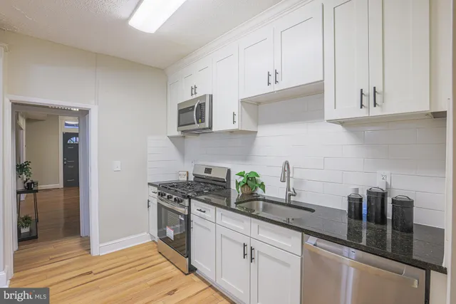a kitchen with stainless steel appliances granite countertop white cabinets and a counter top space