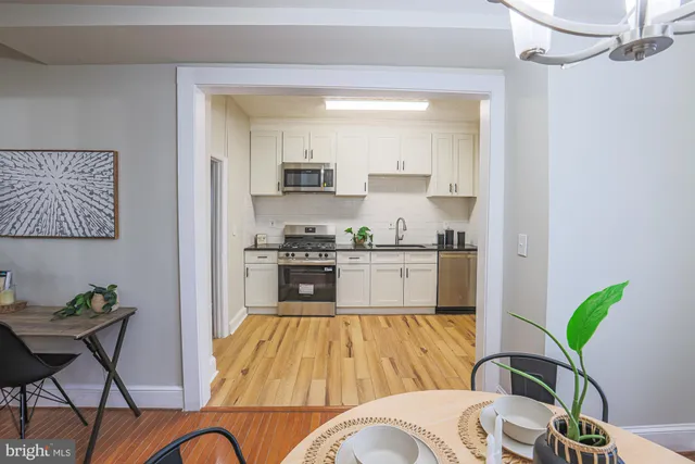 a living room with stainless steel appliances furniture and a kitchen view