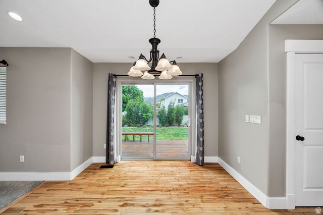 2912 South 1080th Street West Logan, UT 84321 - Photo 16 of 43 Dining area featuring wood-finish flooring, a sliding glass door to the exterior deck, a multi-light chandelier, white trim, and light gray wall paint