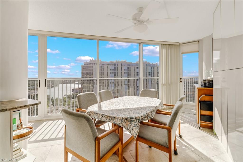 4041 Gulf Shore Boulevard North, Unit PH4 Naples, FL 34103 - Photo 12 of 35 a view of a dining room with furniture large windows and wooden floor