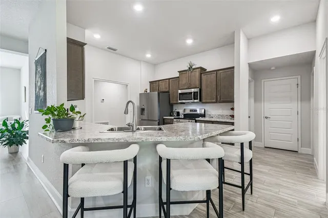 a kitchen with stainless steel appliances granite countertop a stove top oven a sink dishwasher a dining table and chairs with wooden floor