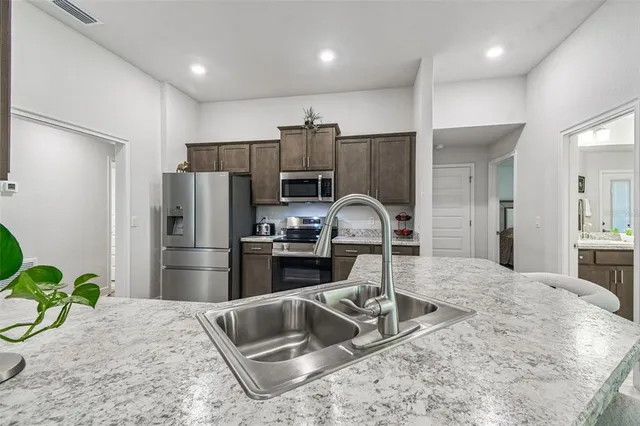 a kitchen with stainless steel appliances a sink cabinets and wooden floor