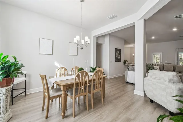 a view of a dining room with furniture a chandelier and wooden floor