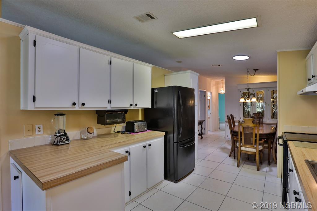 720 Navigators Way Edgewater, FL 32141 - Photo 13 of 35 a kitchen with a refrigerator a table and chairs in it