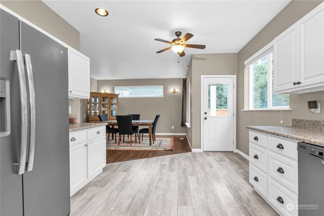 a kitchen with stainless steel appliances a dining table chairs refrigerator and sink