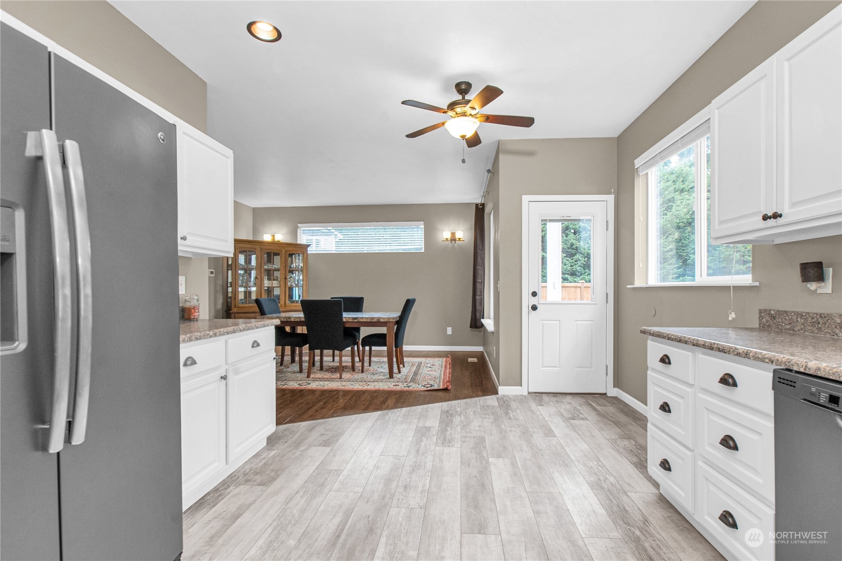 4619 211th Street East Spanaway, WA 98387 - Photo 4 of 36 a kitchen with stainless steel appliances a dining table chairs refrigerator and sink
