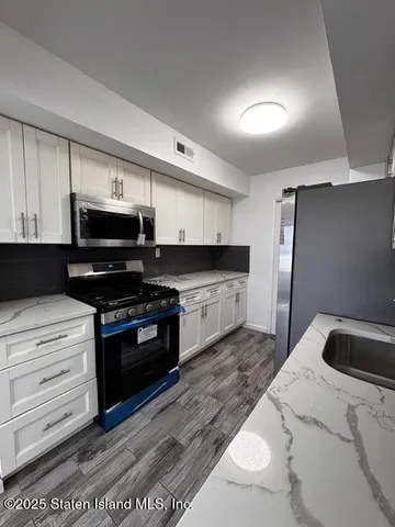 a kitchen with stainless steel appliances kitchen island granite countertop a stove a sink and a microwave