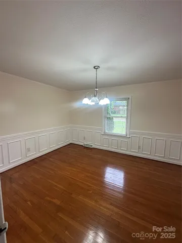 an empty room with wooden floor chandelier fan and windows