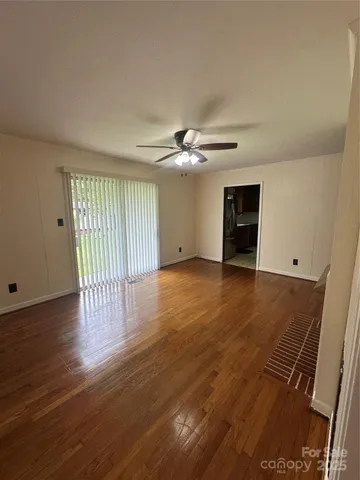 a view of an empty room with wooden floor and a window