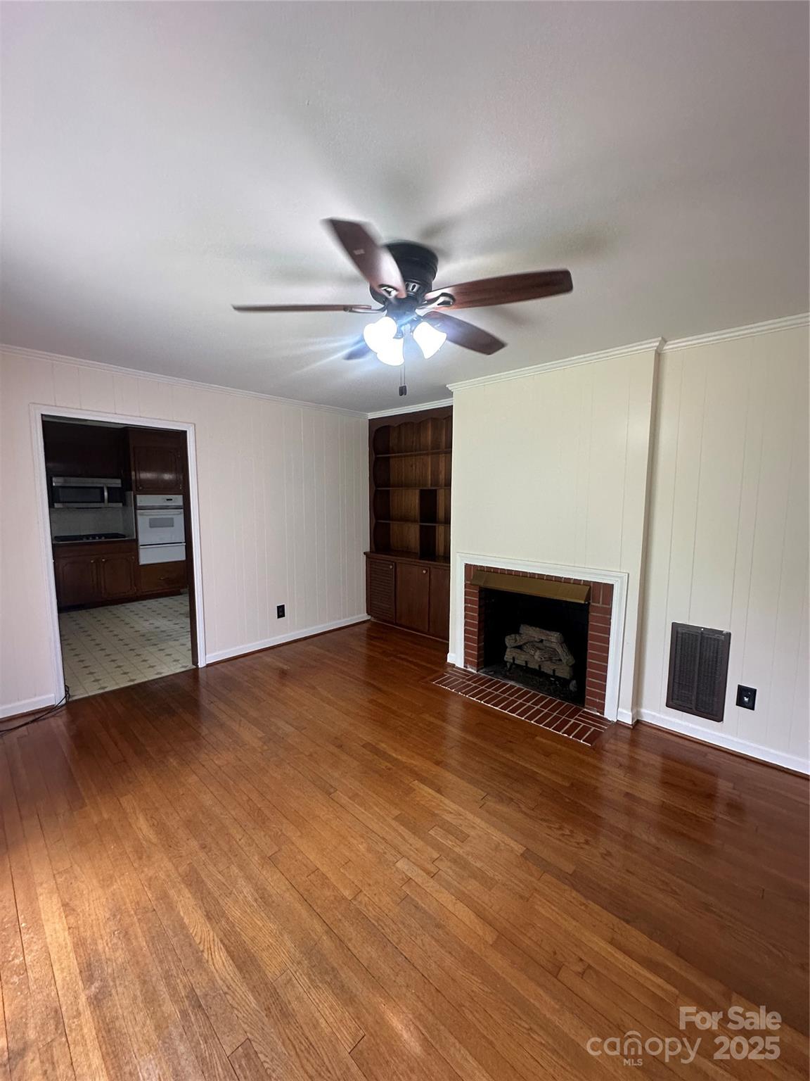 1115 Dumbarton Road Gastonia, NC 28054 - Photo 9 of 20 an empty room with fireplace wooden floor and chandelier