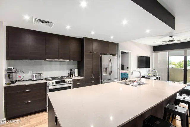 a large kitchen with sink a refrigerator and chairs