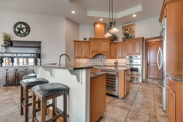 a kitchen with kitchen island granite countertop a stove a sink a refrigerator and a refrigerator