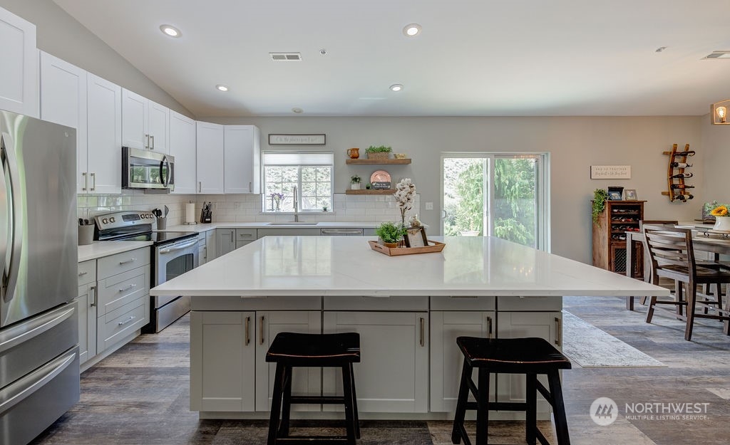 1365 Pitcher Canyon Road Wenatchee, WA 98801 - Photo 11 of 40 a kitchen with stainless steel appliances kitchen island granite countertop a table chairs sink and cabinets