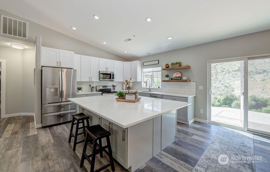 1365 Pitcher Canyon Road Wenatchee, WA 98801 - Photo 12 of 40 a kitchen with stainless steel appliances a refrigerator a stove a sink dishwasher a oven with white cabinets and wooden floor
