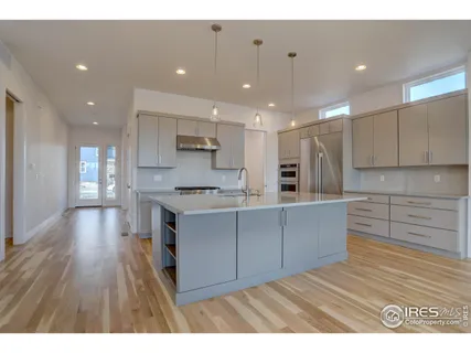 a kitchen with stainless steel appliances granite countertop a refrigerator a sink dishwasher and a stove with wooden floor