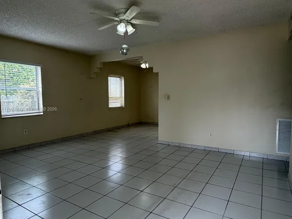 an empty room with windows and fan