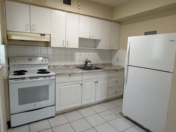 a kitchen with white cabinets and white appliances