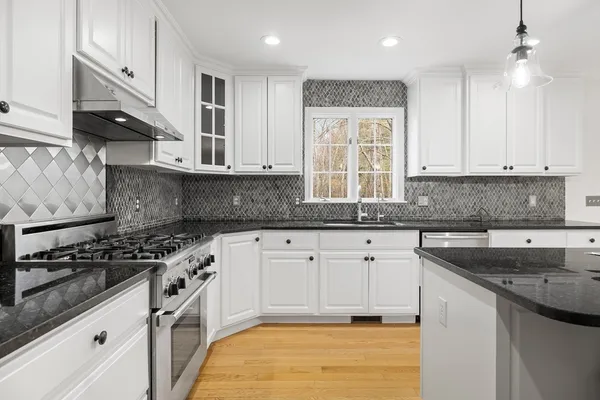 a kitchen with stainless steel appliances granite countertop a sink stove and cabinets