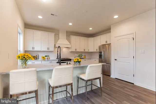 a kitchen with kitchen island granite countertop a sink cabinets and wooden floor