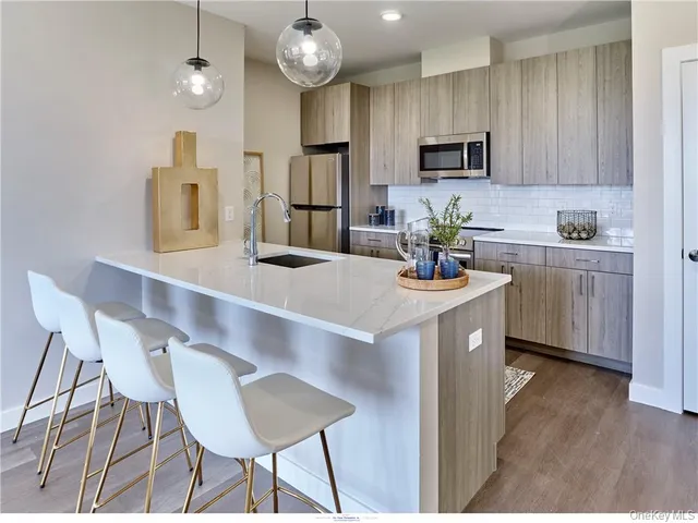 a living room with couches a table and kitchen view with wooden floor