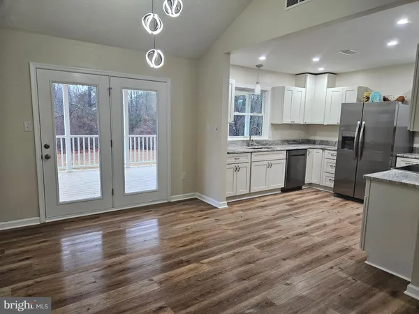 a kitchen with stainless steel appliances granite countertop a stove top oven a sink dishwasher a refrigerator and white cabinets with wooden floor