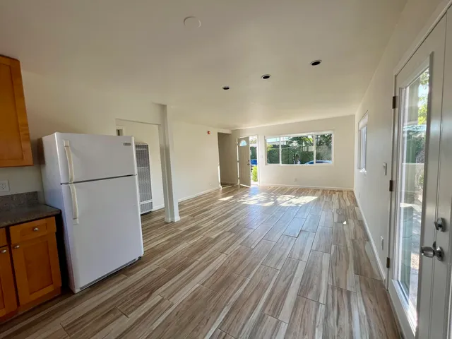 a view of a kitchen with a refrigerator a stove top oven a ceiling fan and wooden floor
