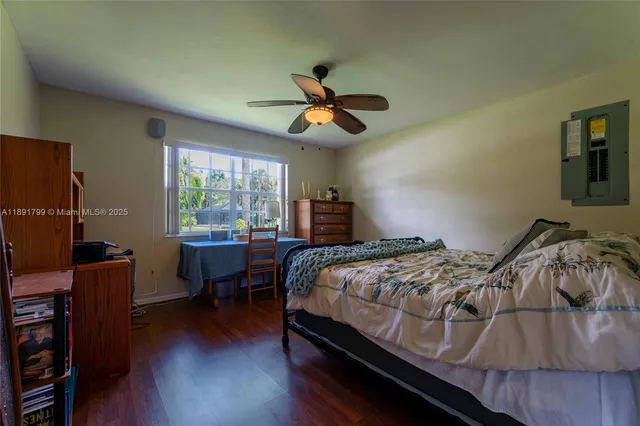 a bedroom with a bed a desk and chair with wooden floor