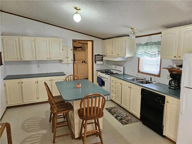 a kitchen with stainless steel appliances granite countertop a stove a sink dishwasher a refrigerator and white cabinets with wooden floor