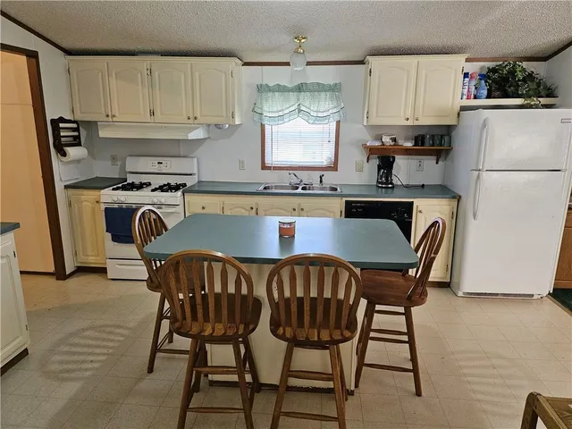 a kitchen with stainless steel appliances granite countertop a dining table chairs a refrigerator and a sink