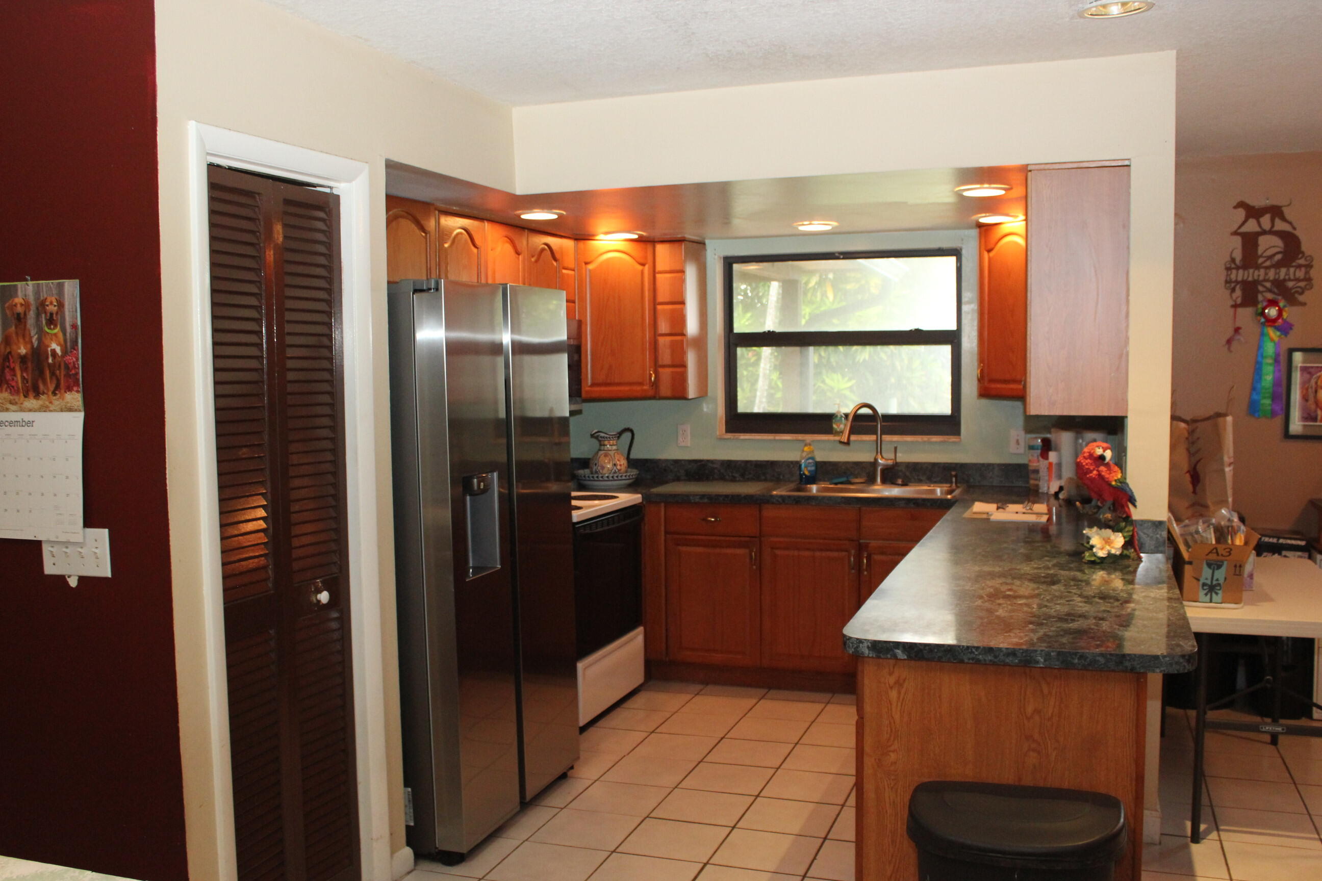 4981 Serafica Drive Lake Worth, FL 33461 - Photo 21 of 44 a kitchen with kitchen island granite countertop a sink stove and refrigerator