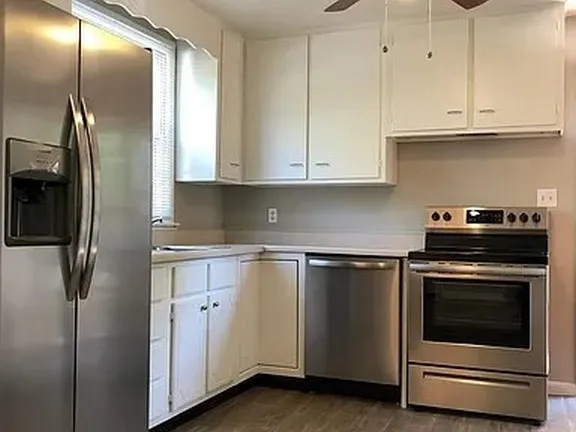 a kitchen with stainless steel appliances granite countertop a stove a refrigerator and a white cabinets