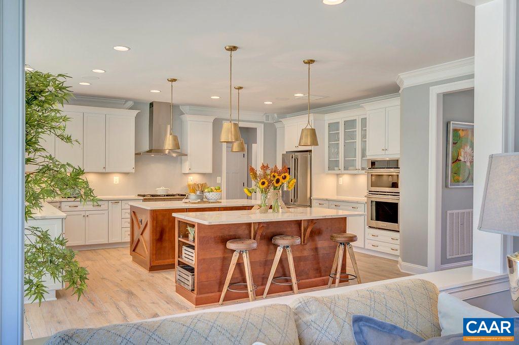2134 Ridgetop Drive Charlottesville, VA 22903 - Photo 12 of 49 a large kitchen with kitchen island a stove a sink a refrigerator and a dining table with wooden floor