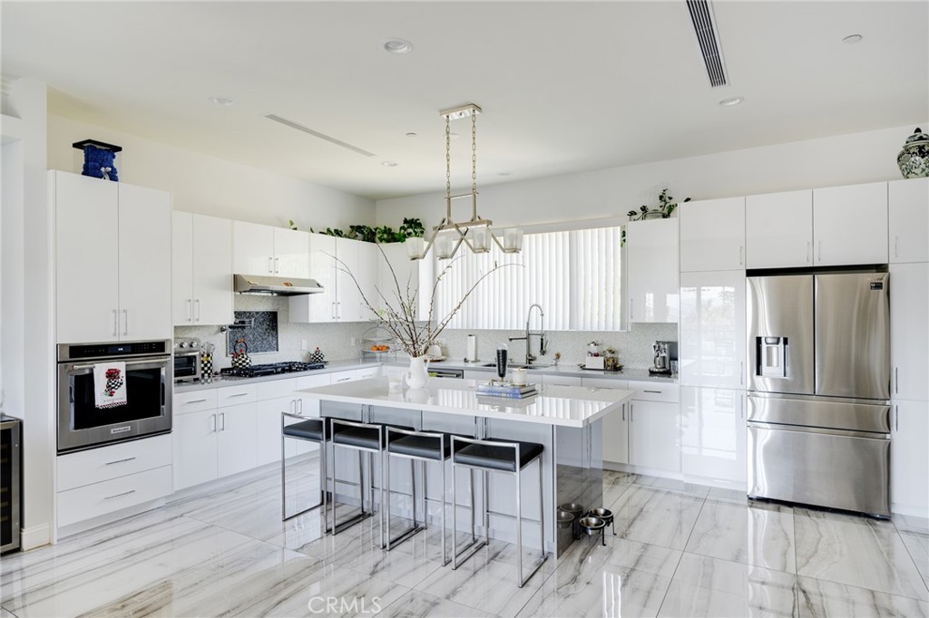 10461 Hillhaven Avenue Tujunga, CA 91042 - Photo 7 of 31 a kitchen with granite countertop a table chairs microwave and refrigerator
