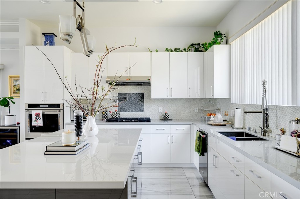 10461 Hillhaven Avenue Tujunga, CA 91042 - Photo 8 of 31 a kitchen with stainless steel appliances kitchen island granite countertop a sink dishwasher and white cabinets with wooden floor