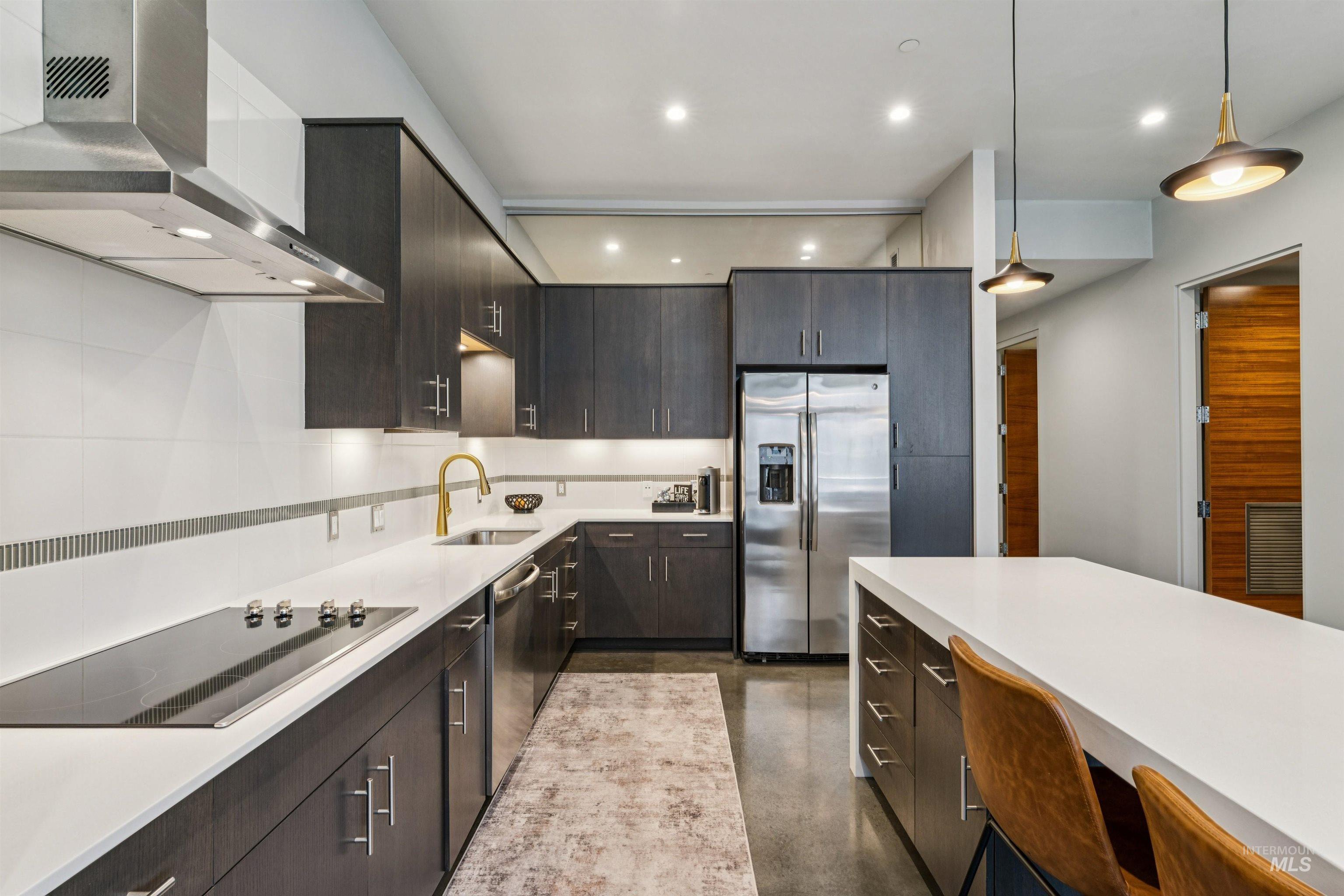 119 South 10th Street, Unit 307 Boise, ID 83702 - Photo 19 of 47 Contemporary kitchen featuring dark wood-finish cabinetry, stainless steel appliances, and a central island with a white countertop