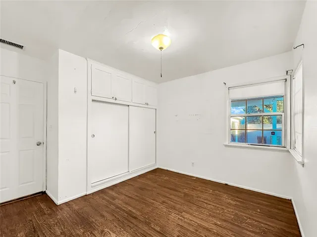 a view of an empty room with window and wooden floor