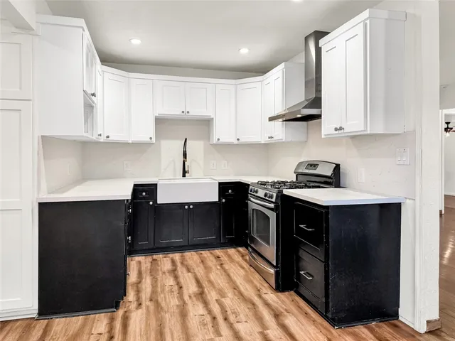 a kitchen with stainless steel appliances granite countertop a refrigerator a sink dishwasher and white cabinets with wooden floor