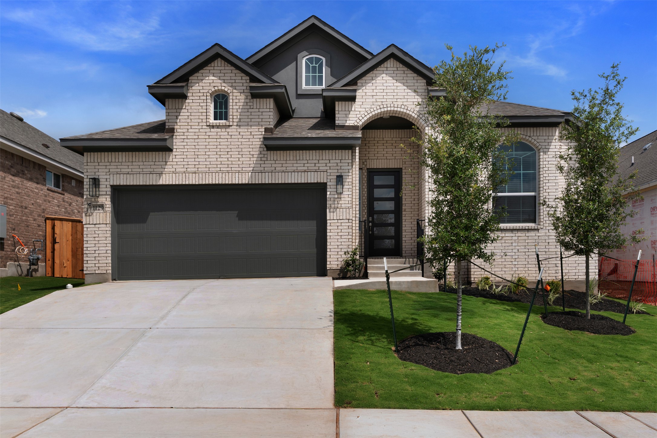 Contemporary two-story residence featuring a light brick facade and dark grey trim accents