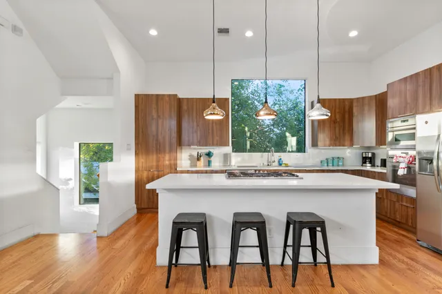 a kitchen with stainless steel appliances granite countertop a kitchen island a stove a cabinets a sink and a refrigerator