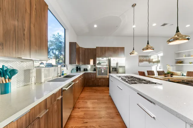 a kitchen with stainless steel appliances a large stove a sink a oven a dining table and chairs